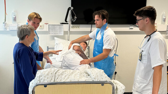 Bildet viser mannlige sykepleierstudenter som steller medstudent.
