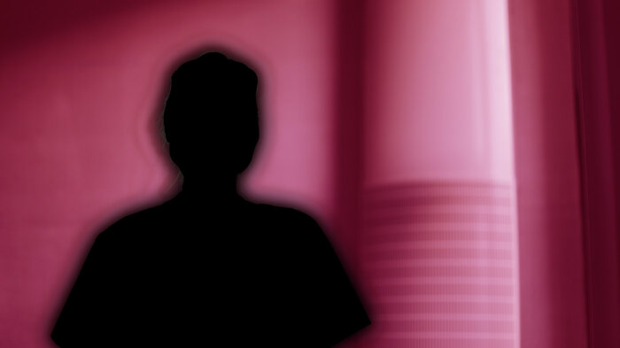 Bilde viser silluett av et menneske på rød bakgrunn