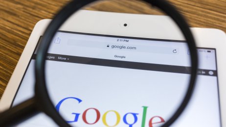 Google-søk Bildet viser et forstørrelsesglass som holdes over Googles søkeside