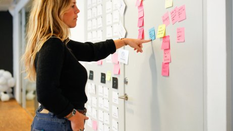 En kvinne studerer post-it lapper klistret opp på en dør. Bildet viser en kvinne som studerer post-it lapper klistret opp på en dør.