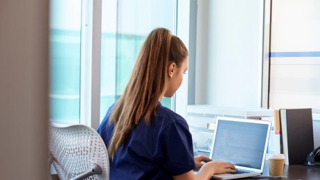 Sykepleier Bildet viser en sykepleier som sitter alene foran pc-en.