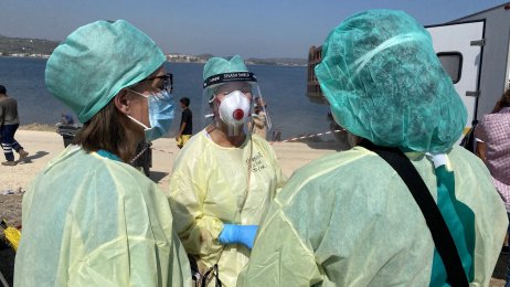Medisinsk innsatsteam Bildet viser helsepersonell i smittevernutstyr på en strand.
