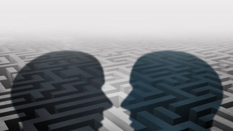 mennesker Bildet viser silhuetten av to mennesker som står ovenfor hverandre. I bakgrunnen kan man skimte en labyrint.