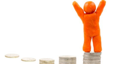 Plastelinafigur Bildet viser en orange plastelinafigur som står oppe en høyde med mynter