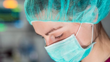 Bildet viser nærbildet av en kvinne med munnbind og hårnett.