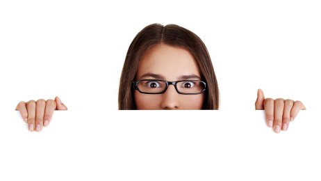 Overrasket kvinne Bildet viser en kvinne med oppsperrede øyne som titter over en kant