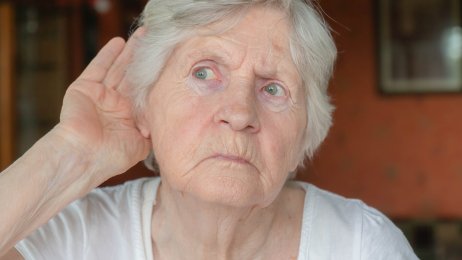 Hørsel og demens Bildet viser en eldre dame som har hånden bak øret for å lytte.