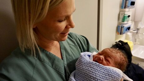 Bildet viser jordmoren Helene Normann Furnes med et nyfødt barn i armene.