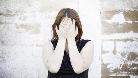 Bildet viser en kvinne som dekker ansiktet med hendene