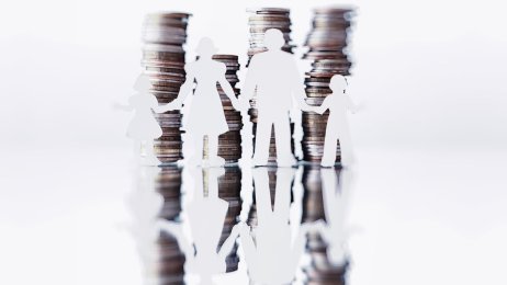 Økonomi og helse Bildet viser en familie i silhuett med mynter stablet oppå hverandre i bakgrunnen.