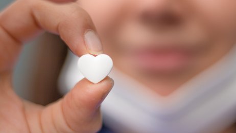 Sykepleier Bildet viser en sykepleier som holder et lite hjerte mellom fingrene.