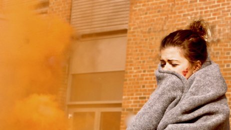 Krisehåndtering Bildet viser en skadet kvinne med et pledd rundt seg. Det er røykskyer rundt henne.