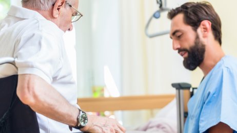 Pleie Bildet viser en sykepleier som hjelper en eldre mann i rullestol