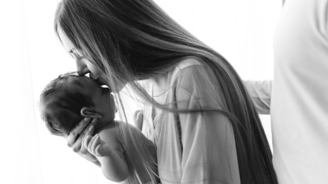 Barnepalliasjon Bildet viser en mor som holder sitt spedbarn i armene mens hun kysser barnet på hodet. Mannen hennes holder rundt henne.