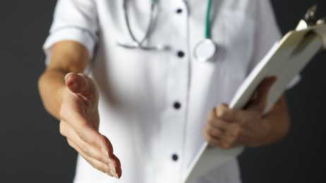 Bildet viser en sykepleier som rekker frem hånden for å hilse