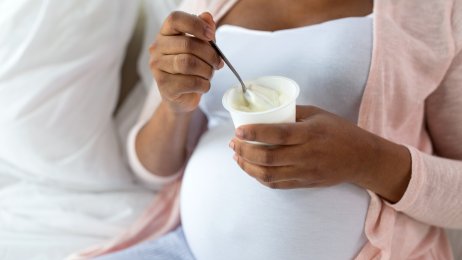 Bildet viser en gravid kvinne som spiser yoghurt