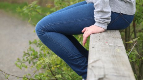 Bildet viser et utsnitt av en jente som sitter på et gelender.