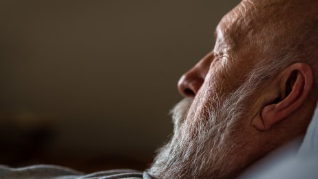 Bildet viser en eldre mann i profil med lukkede øyne. Han ligger i sengen.