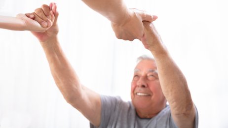 Smilende eldre mann får hjelp av en pleier. Smilende eldre mann får hjelp av en pleier.