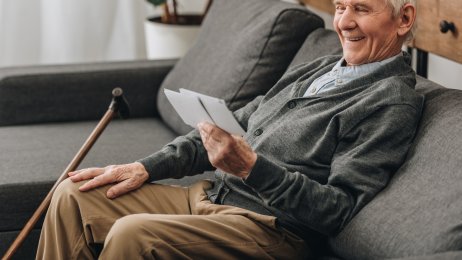 Eldre mann ser på bilder Eldre mann som ser på bilder og smiler