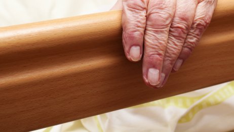 Edre mann i sengen på et pleiehjem. Bildet viser en hånden til en eldre mann som ligger i sengen på et pleiehjem.