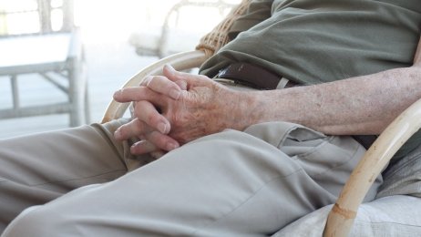 Ensom mann. Illustrasjonsfoto: Colourbox Bildet viser deler av en eldre person som sitter med hendene i fanget.