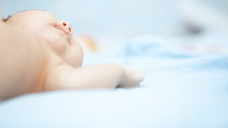 Baby Bildet viser en guttebaby på lyseblått teppe.