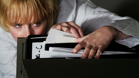 Kvinne som ser i arkiv, papirer eller journaler.