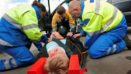 Bildet viser tre ambulansepersonell som gir førstehjelp til en bevisstløs person som har krasjet med bilen.