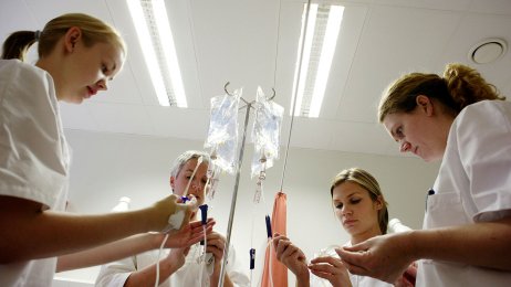 Studenter i praksis Bildet viser studenter i praksis som står med en væskepose over ei seng