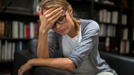 Utbrent Bildet viser en kvinne som sitter i en stol og hviler pannen i hånden.