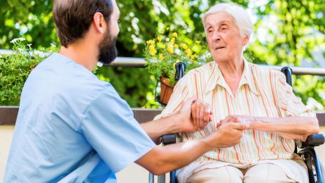 Holde hender Bildet viser en pleier som holder hendene til en eldre kvinne som sitter i rullestol