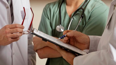 Journalføring Leger og sykepleiere står og sjekker en journal til en pasient.