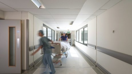 helsevesen, arbeidstid Bildet viser helsearbeidere som triller en seng.