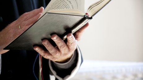 Prest Prest som holder en salmebok i hendene