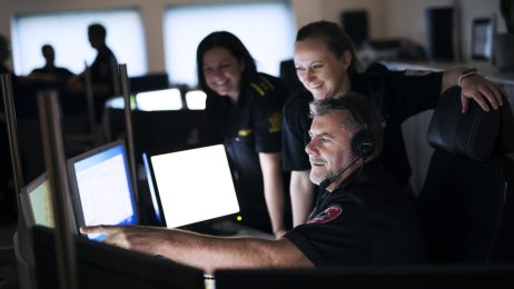 Bildet viser operasjonsleder 112, vaktleder 110 og operatør 113 som diskuterer foran en pc-skjerm.