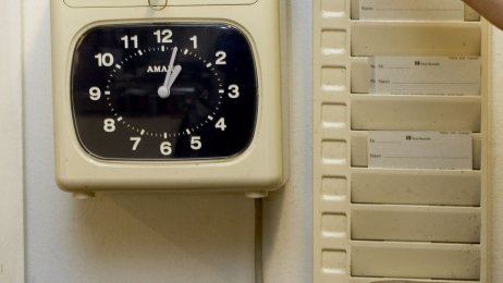 arbeidstid, stemplingsur Bildet viser en hånd som drar et kort i et stemplingsur.