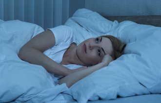 Bildet viser en dame som ligger i sengen og ikke får sove