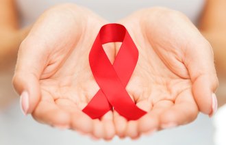 Bildet viser hender som holder en rød sløyfe som symboliserer hiv/aids