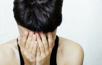 Bildet viser en ung dame eller jente som fortvilet holder hodet i hendene.