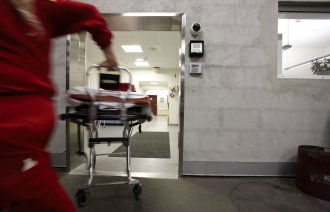 En mann i ambulanseuniform løper inn på sykehuset med en båre