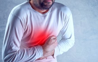 Mann med smerter holder seg for magen.