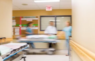 Bildet viser helsepersonell som triller en pasient i korridoren på et sykehus