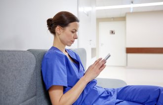 Sykepleierstudent eller veileder som leser på smarttelefonen