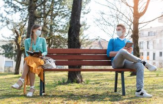 bildet viser et par på benk med avstand og munnbind