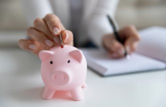 Bildet viser en som putter penger i en sparegris