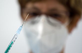 Bildet viser en helsearbeider med en sprøyte.