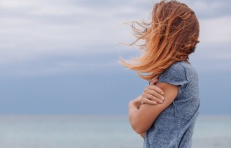 Bildet viser en tankefull kvinne som ser utover sjøen.