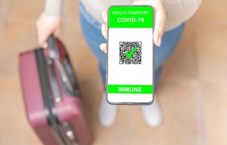 Bildet viser en kvinne med en koffert som viser, med mobilen sin, at hun er vaksinert for covid-19