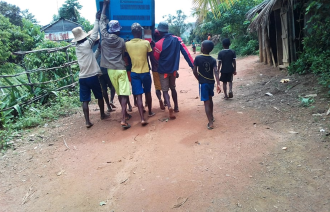 Bildet viser transport av vaksinar på Madagaskar, der kjølebagen med vaksinar transporteres av sju personer som bærer sammen